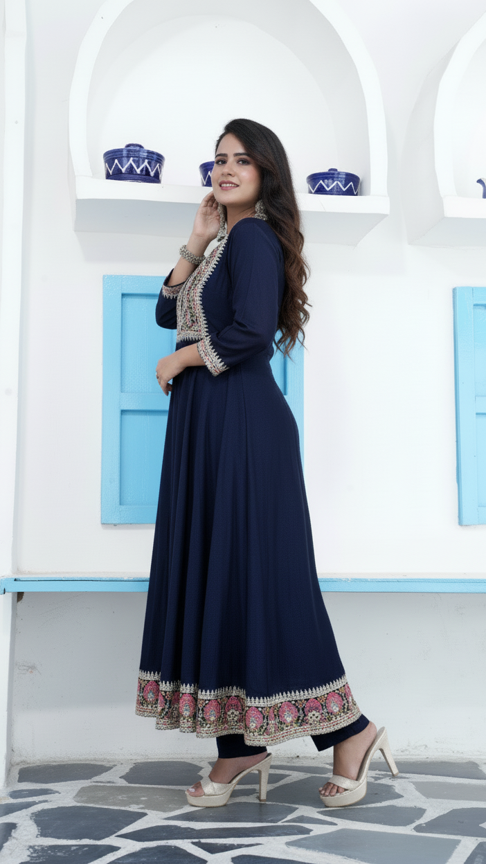Woman in a navy blue dress with floral patterns standing in front of a white wall with blue accents.
